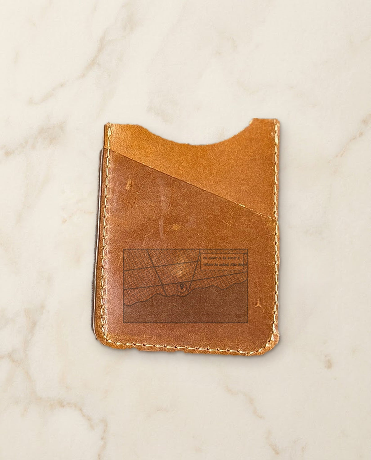 Street map with pin and coordinates engraved on a cognac leather card holder
