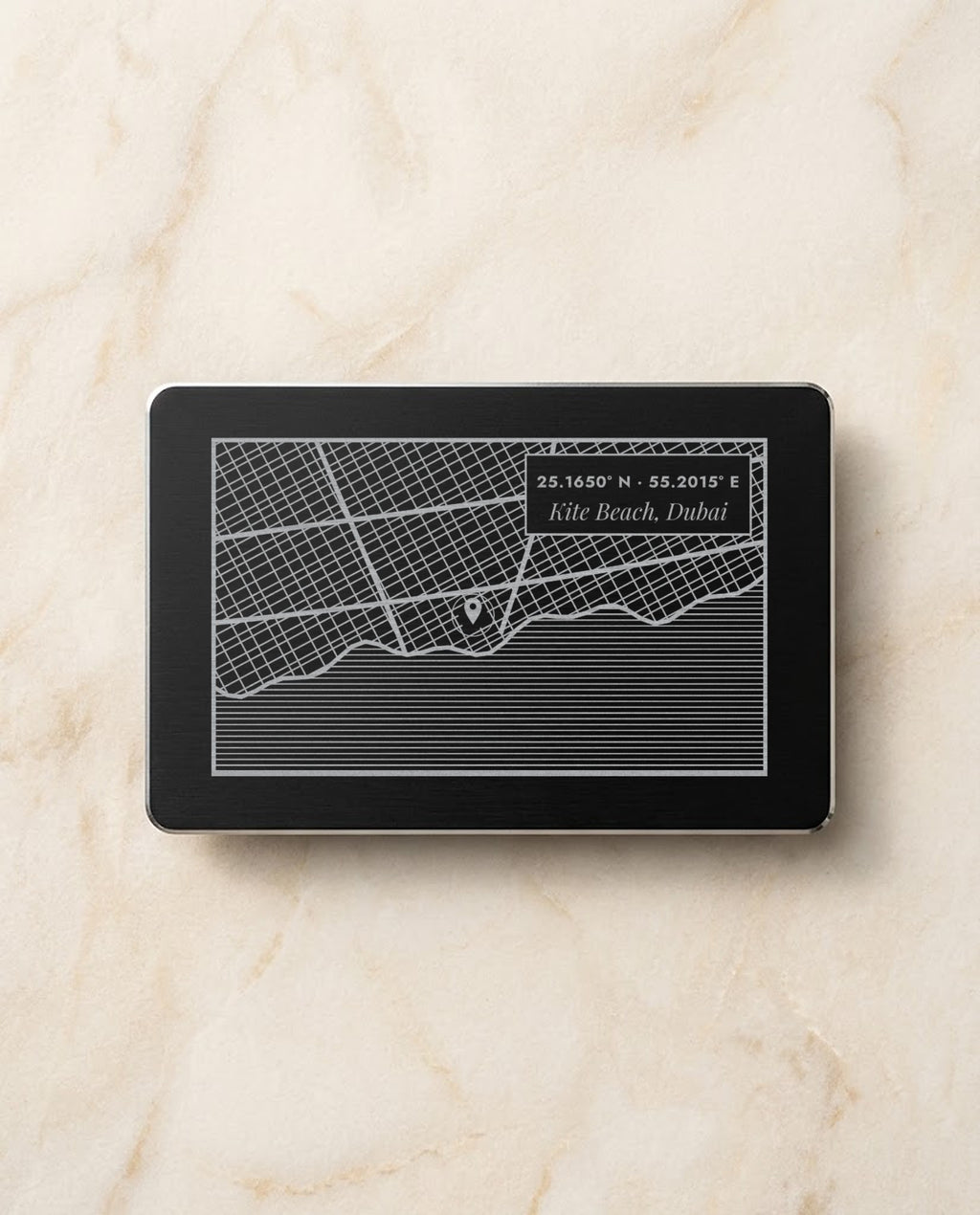 Street map with pin and coordinates engraved on a black metal card
