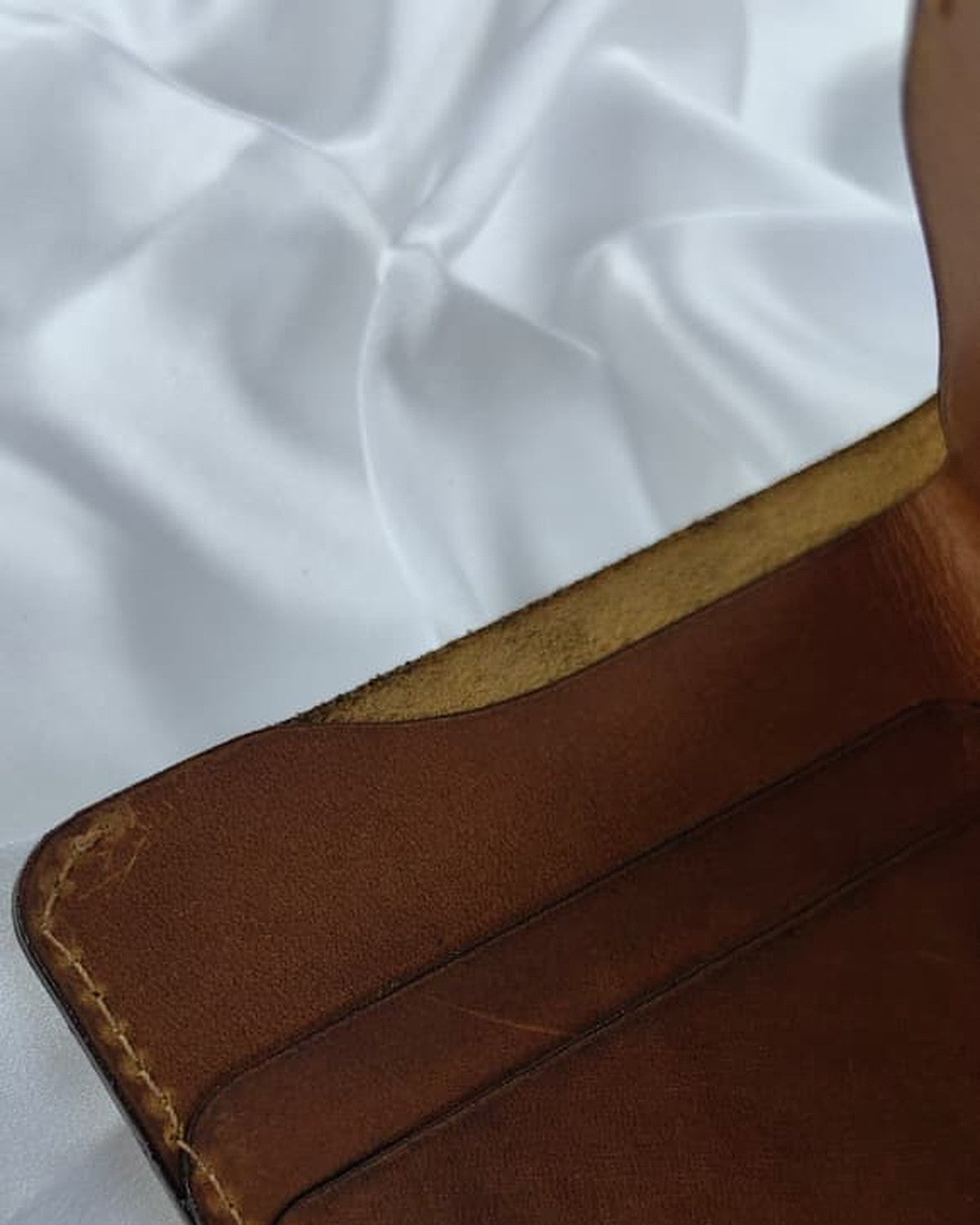 Full-grain leather bifold wallet, close-up of the stitched edge
