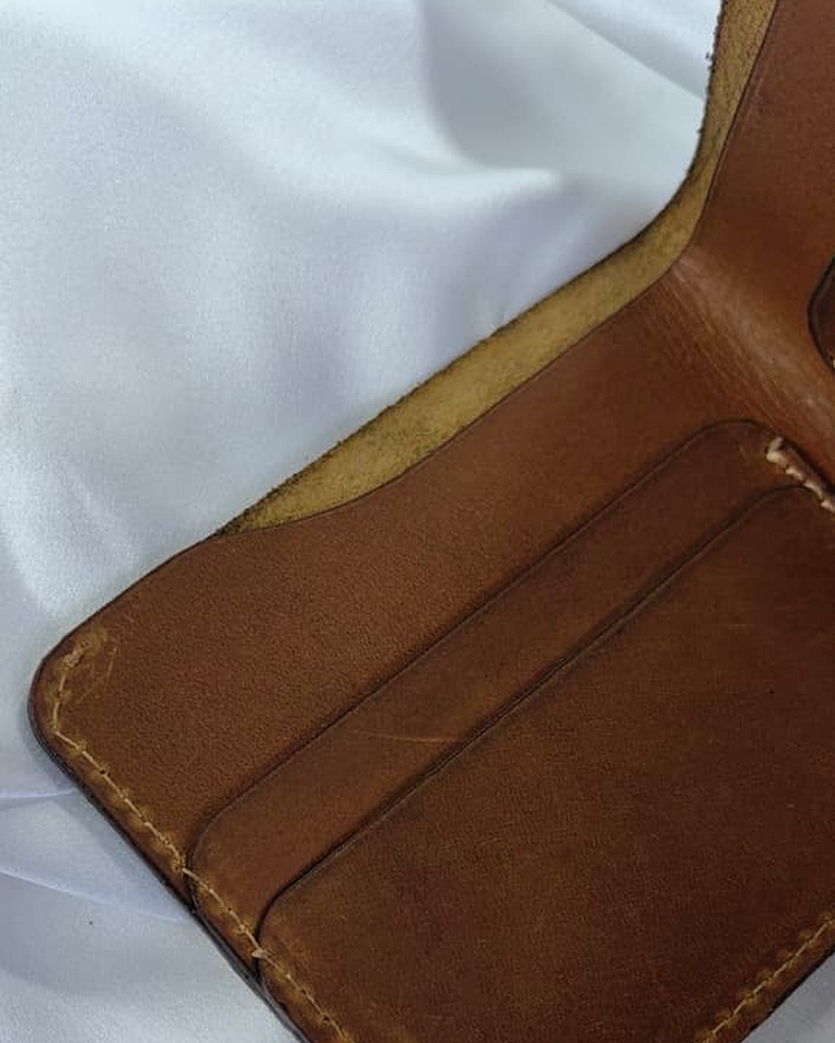 Full-grain leather bifold wallet, open, showing the card slots
